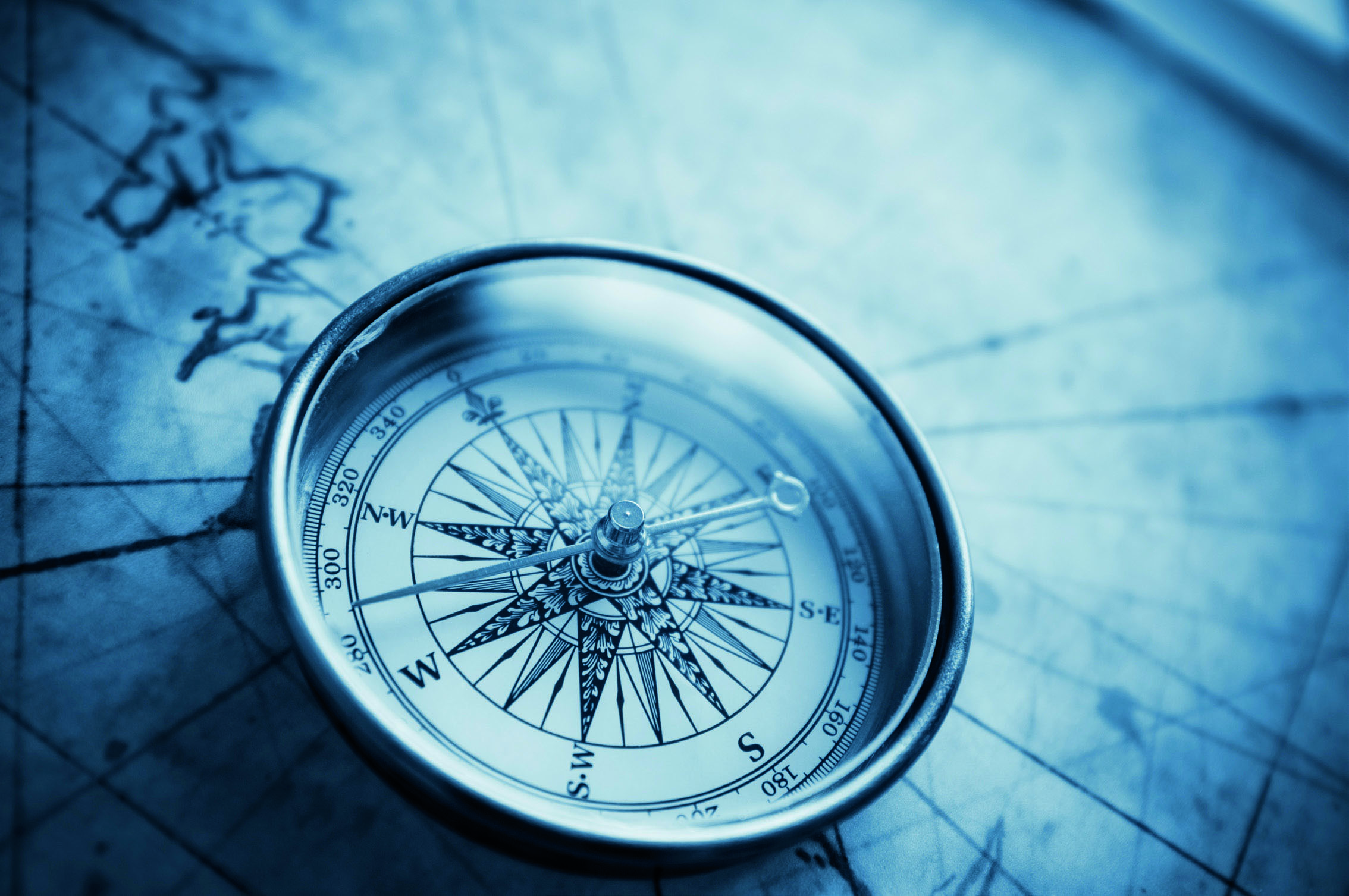 Compass on old map with blue tone.