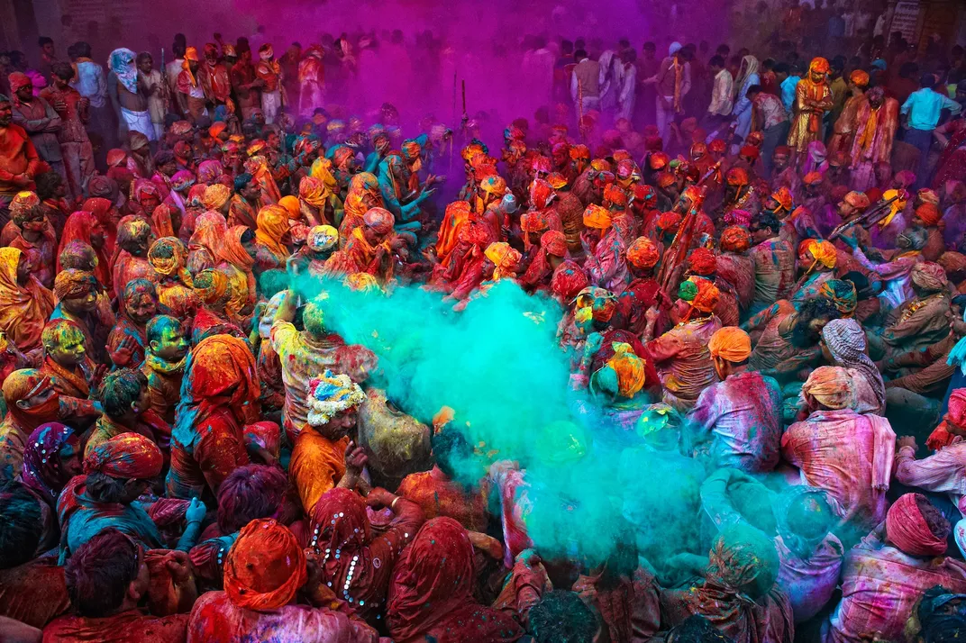 a blue powder is thrown into a crowd during Holi Festival