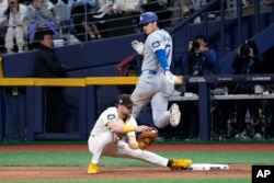 Los Angeles Dodgers designated hitter Shohei Ohtani, top, is forced out at first by San Diego Padres first baseman Jake Cronenworth during the seventh inning of an opening day baseball game at the Gocheok Sky Dome in Seoul, South Korea, March 20, 2024.