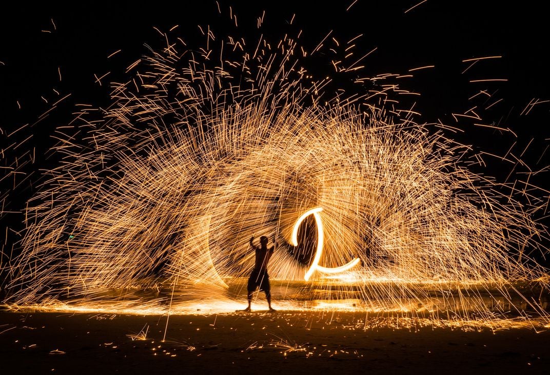 7 - A man performs a spectacular fire show on the beach.